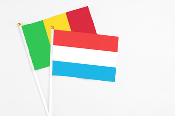 Luxembourg and Mali stick flags on white background. High quality fabric, miniature national flag. Peaceful global concept.White floor for copy space.