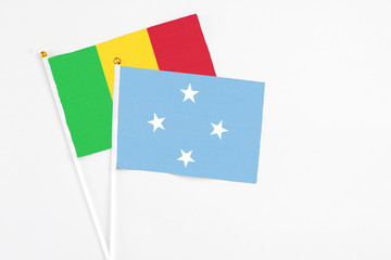 Micronesia and Mali stick flags on white background. High quality fabric, miniature national flag. Peaceful global concept.White floor for copy space.
