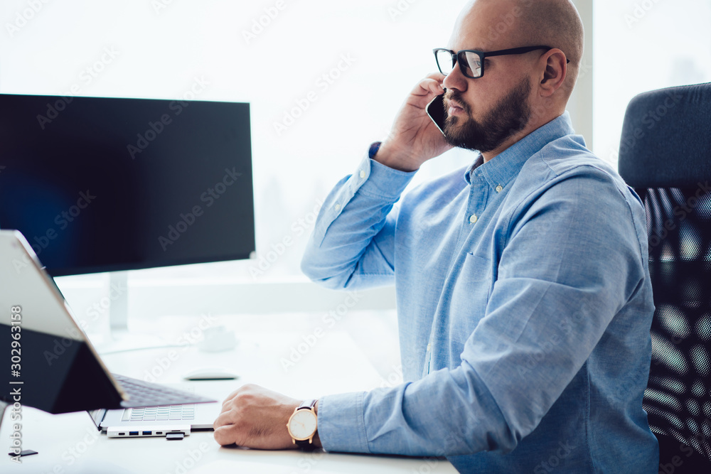 Wall mural serious adult man speaking on phone in office