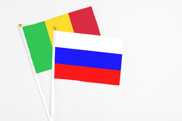 Russia and Mali stick flags on white background. High quality fabric, miniature national flag. Peaceful global concept.White floor for copy space.