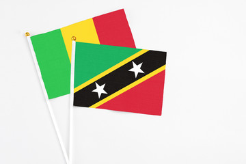 Saint Kitts And Nevis and Mali stick flags on white background. High quality fabric, miniature national flag. Peaceful global concept.White floor for copy space.