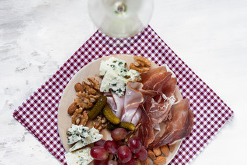 Delicious aperetif for evening home party: wooden borad with french blue cheese, bacon, walnut and almond, italian sweet grapes. Closeup, white background