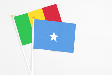 Somalia and Mali stick flags on white background. High quality fabric, miniature national flag. Peaceful global concept.White floor for copy space.
