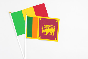Sri Lanka and Mali stick flags on white background. High quality fabric, miniature national flag. Peaceful global concept.White floor for copy space.