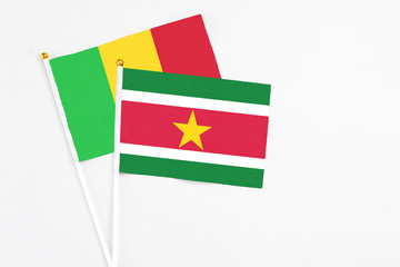 Suriname and Mali stick flags on white background. High quality fabric, miniature national flag. Peaceful global concept.White floor for copy space.