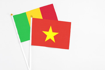 Vietnam and Mali stick flags on white background. High quality fabric, miniature national flag. Peaceful global concept.White floor for copy space.