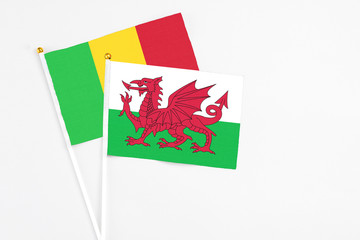 Wales and Mali stick flags on white background. High quality fabric, miniature national flag. Peaceful global concept.White floor for copy space.