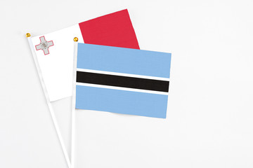 Botswana and Malta stick flags on white background. High quality fabric, miniature national flag. Peaceful global concept.White floor for copy space.