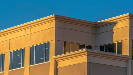 Panorama Facade of a commercial building with large glass windows against clear blue sky