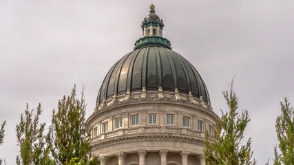 Panorama Famous Utah State Capitol Building dome framed with trees against cloudy sky
