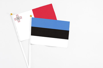 Estonia and Malta stick flags on white background. High quality fabric, miniature national flag. Peaceful global concept.White floor for copy space.