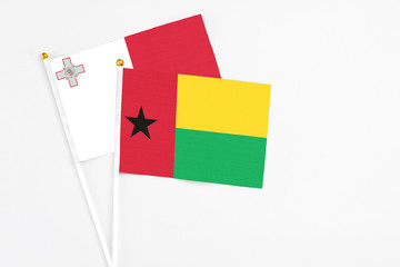 Guinea Bissau and Malta stick flags on white background. High quality fabric, miniature national flag. Peaceful global concept.White floor for copy space.