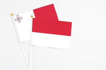 Indonesia and Malta stick flags on white background. High quality fabric, miniature national flag. Peaceful global concept.White floor for copy space.
