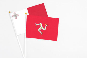 Isle Of Man and Malta stick flags on white background. High quality fabric, miniature national flag. Peaceful global concept.White floor for copy space.