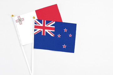 Fototapeta premium New Zealand and Malta stick flags on white background. High quality fabric, miniature national flag. Peaceful global concept.White floor for copy space.