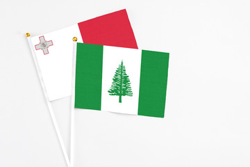 Norfolk Island and Malta stick flags on white background. High quality fabric, miniature national flag. Peaceful global concept.White floor for copy space.