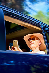 Portrait of woman sitting in the car with mobile in hand