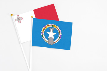 Northern Mariana Islands and Malta stick flags on white background. High quality fabric, miniature national flag. Peaceful global concept.White floor for copy space.