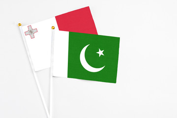 Pakistan and Malta stick flags on white background. High quality fabric, miniature national flag. Peaceful global concept.White floor for copy space.