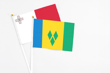 Saint Vincent And The Grenadines and Malta stick flags on white background. High quality fabric, miniature national flag. Peaceful global concept.White floor for copy space.