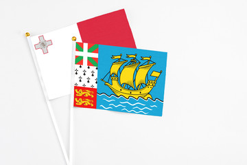 Saint Pierre And Miquelon and Malta stick flags on white background. High quality fabric, miniature national flag. Peaceful global concept.White floor for copy space.