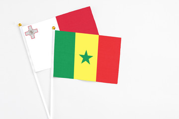 Senegal and Malta stick flags on white background. High quality fabric, miniature national flag. Peaceful global concept.White floor for copy space.