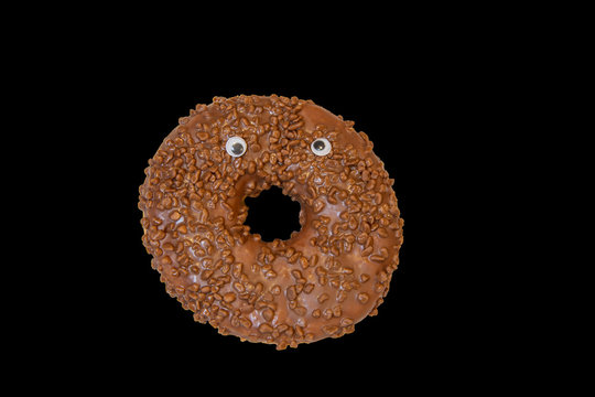 An isolated image of a doughnut with googly eyes on a black background
