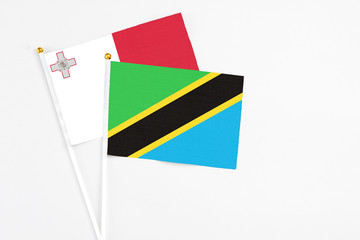 Tanzania and Malta stick flags on white background. High quality fabric, miniature national flag. Peaceful global concept.White floor for copy space.
