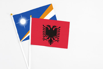 Obraz na płótnie Canvas Albania and Marshall Islands stick flags on white background. High quality fabric, miniature national flag. Peaceful global concept.White floor for copy space.