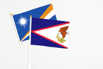 American Samoa and Marshall Islands stick flags on white background. High quality fabric, miniature national flag. Peaceful global concept.White floor for copy space.