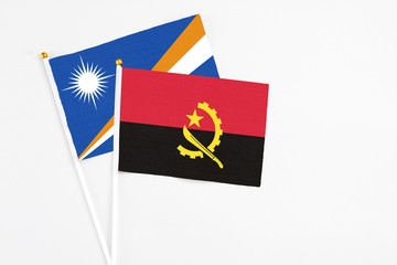 Angola and Marshall Islands stick flags on white background. High quality fabric, miniature national flag. Peaceful global concept.White floor for copy space.