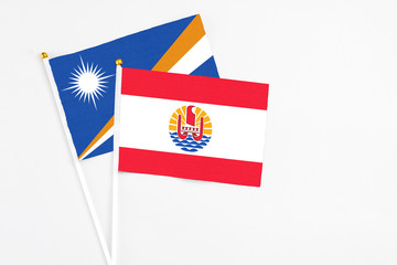 French Polynesia and Marshall Islands stick flags on white background. High quality fabric, miniature national flag. Peaceful global concept.White floor for copy space.