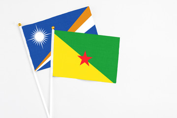 French Guiana and Marshall Islands stick flags on white background. High quality fabric, miniature national flag. Peaceful global concept.White floor for copy space.