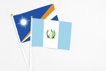 Guatemala and Marshall Islands stick flags on white background. High quality fabric, miniature national flag. Peaceful global concept.White floor for copy space.