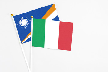 Italy and Marshall Islands stick flags on white background. High quality fabric, miniature national flag. Peaceful global concept.White floor for copy space.