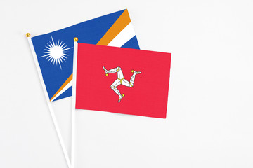 Isle Of Man and Marshall Islands stick flags on white background. High quality fabric, miniature national flag. Peaceful global concept.White floor for copy space.