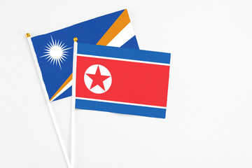 North Korea and Marshall Islands stick flags on white background. High quality fabric, miniature national flag. Peaceful global concept.White floor for copy space.