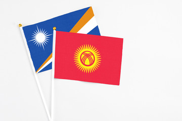 Kyrgyzstan and Marshall Islands stick flags on white background. High quality fabric, miniature...