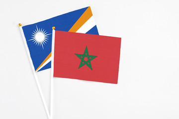 Morocco and Marshall Islands stick flags on white background. High quality fabric, miniature national flag. Peaceful global concept.White floor for copy space.