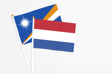 Netherlands and Marshall Islands stick flags on white background. High quality fabric, miniature national flag. Peaceful global concept.White floor for copy space.