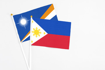 Philippines and Marshall Islands stick flags on white background. High quality fabric, miniature national flag. Peaceful global concept.White floor for copy space.