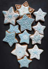 Homemade gingersnaps coverd icing on the dark plate: snowflakes and stars; delicious cookies with Christmas shapes