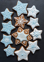 Homemade gingersnaps coverd icing on the dark plate: snowflakes and stars; delicious cookies with Christmas shapes
