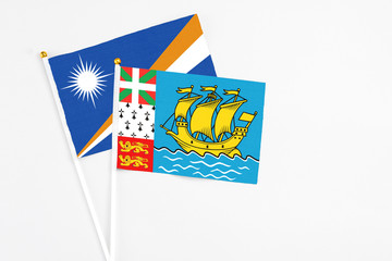 Saint Pierre And Miquelon and Marshall Islands stick flags on white background. High quality fabric, miniature national flag. Peaceful global concept.White floor for copy space.