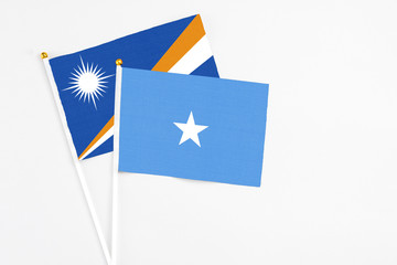 Somalia and Marshall Islands stick flags on white background. High quality fabric, miniature national flag. Peaceful global concept.White floor for copy space.