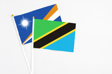 Tanzania and Marshall Islands stick flags on white background. High quality fabric, miniature national flag. Peaceful global concept.White floor for copy space.