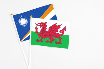 Wales and Marshall Islands stick flags on white background. High quality fabric, miniature national flag. Peaceful global concept.White floor for copy space.