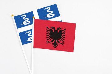 Albania and Martinique stick flags on white background. High quality fabric, miniature national flag. Peaceful global concept.White floor for copy space.