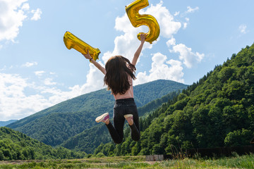 Teenage girl jumping with 15 number outdoor in mountains