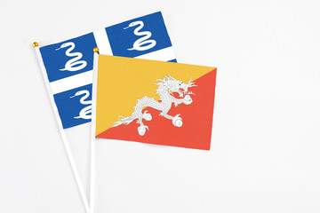Bhutan and Martinique stick flags on white background. High quality fabric, miniature national flag. Peaceful global concept.White floor for copy space.